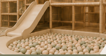 Soft play area with a cream slide and a pastel ball pit in a woven rattan play structure
